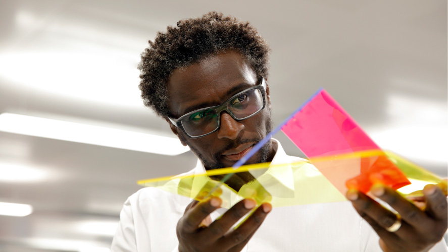 Un uomo con gli occhiali tiene in mano un foglio di carta vivace, che mostra un'esplosione di colori.