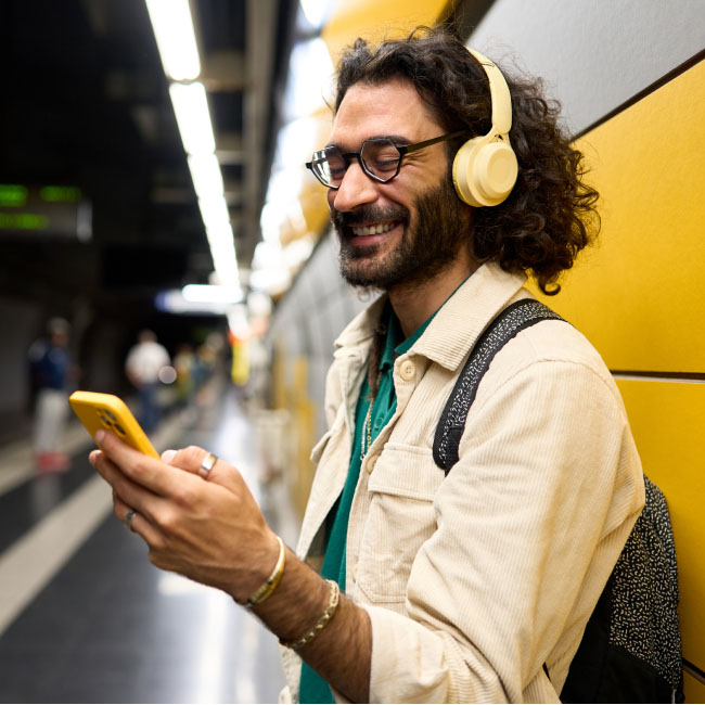 A man with curly hair and glasses checking his phone.