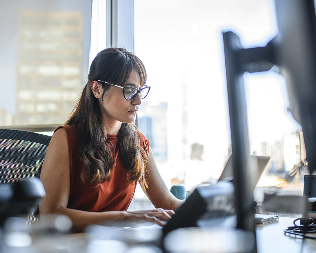 Microsoft 365 Backup - Businesswoman working on a laptop next to a bright exterior window